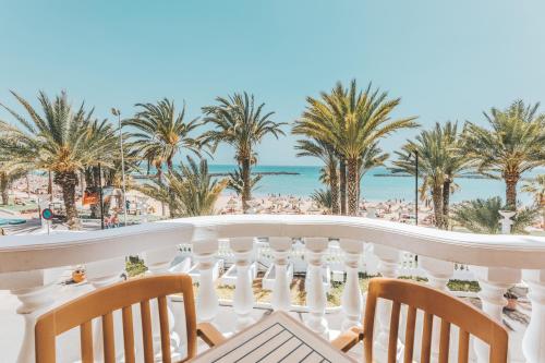 a balcony with a view of the beach and palm trees at Hotel Cleopatra Palace in Playa de las Americas