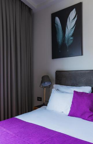 a bedroom with a white bed with a purple pillow at Kalvin Boutique Hotel by Levinsky Market Tel-Aviv in Tel Aviv