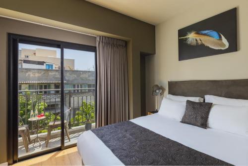 um quarto com uma cama e uma grande janela em Kalvin Boutique Hotel by Levinsky Market Tel-Aviv em Tel Aviv