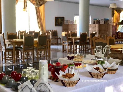 a room with tables and chairs with food on a table at Shkreli Resort Qafeshtame in Krujë