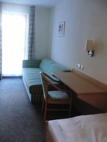 a hotel room with a couch and a desk and a table at Hotel Angerer in Vilseck