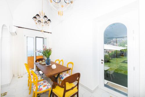 a dining room with a wooden table and yellow chairs at Hotel Eden Roc Suites in Positano