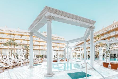a swimming pool in a hotel with chairs and a swimming poolvisorvisor at Hotel Cleopatra Palace in Playa de las Americas