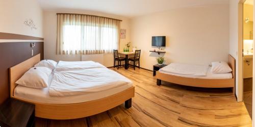 ein Hotelzimmer mit 2 Betten und einem Tisch in der Unterkunft Gästehaus Moser in Mönchhof