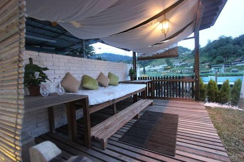 a wooden deck with a bench under a white umbrella at Tung's Factoria Cameron Highland in Cameron Highlands