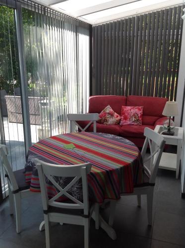 a living room with a red couch and a table and chairs at La conciergerie in Hotton