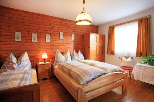 Un dormitorio con dos camas y una pared de madera. en Landhaus Hinterebenhub, en Hopfgarten im Brixental