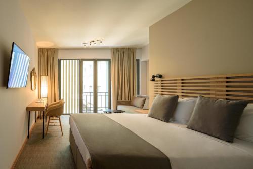 アテネにあるFos DownTown Suitesの大きなベッドとデスクが備わるホテルルームです。