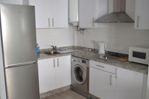 a kitchen with white cabinets and a washing machine at Modern studio flat close to Plaza Merced in Málaga