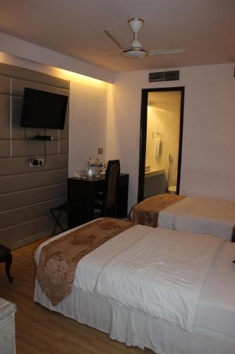 a hotel room with two beds and a television at Hotel Jukaso Inn Down Town in New Delhi