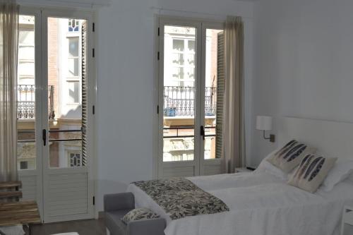a white bedroom with a bed and a balcony at Modern studio flat close to Plaza Merced in Málaga