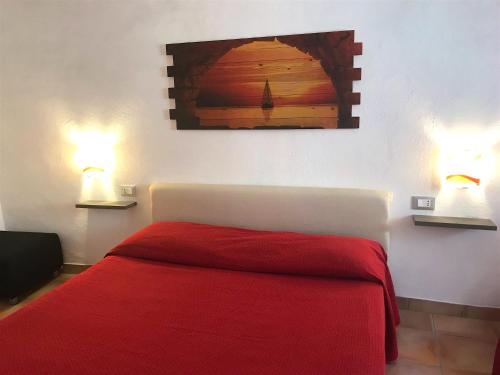 a bedroom with a red bed with two lights on the wall at Casa al Castello in Isola del Giglio