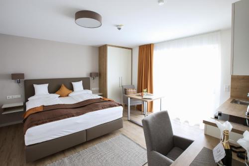 - une chambre avec un grand lit et une chaise dans l'établissement Appartementhotel Fidelio, à Bad Füssing