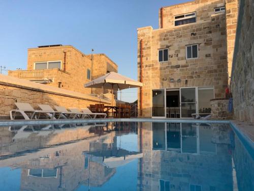 a swimming pool with chairs and a building at Villa Chossie in Żejtun