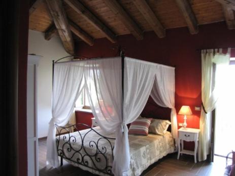 a bedroom with a canopy bed with red walls at Il Ghiro Dormiglione in Cocconato