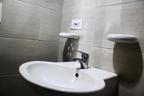 a bathroom sink with a faucet on a wall at Hotel Royal Suite in Manizales