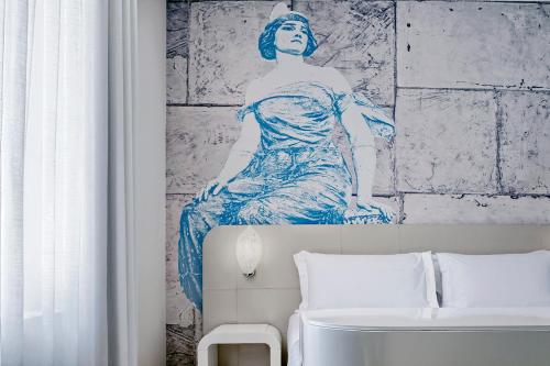 a painting of a woman on a wall above a bed at Ausonia Hungaria Wellness & Lifestyle in Venice-Lido