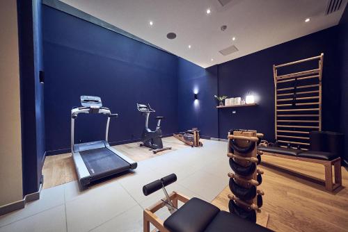 a gym with a blue wall and tread machines at Maison Nô - Hôtel et Rooftop in Lyon