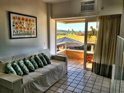 a living room with a couch and a large window at Gavoa Beach Resort Flat 201 D - Praia de Mangue Seco, Igarassu-Pe in Igarassu