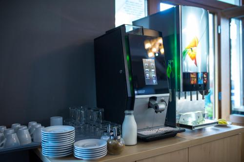 a counter with plates and cups and a coffee machine at JBX Resort Apartments Lipno in Lipno nad Vltavou