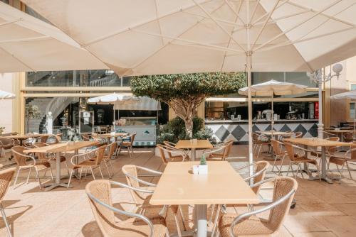 an empty restaurant with tables and chairs and umbrellas at Hotel Cleopatra Palace in Playa de las Americas