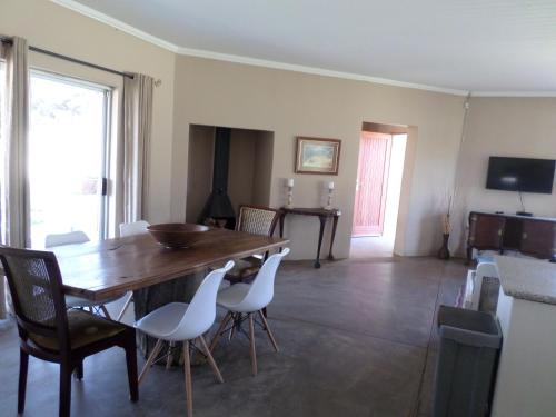 a dining room with a wooden table and white chairs at Out Of Nature Country Lodge in Windhoek