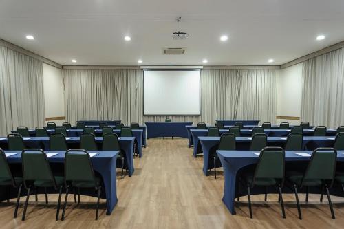 a conference room with blue tables and chairs and a screen at Hotel The Premium in Osasco