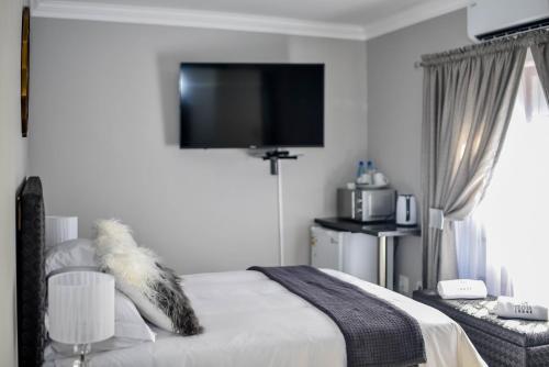 um quarto com uma cama e uma televisão de ecrã plano na parede em Clivia Lodge em Louis Trichardt