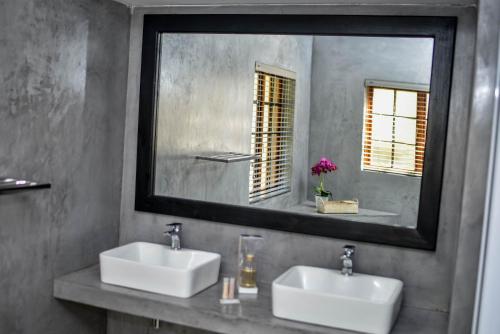 a bathroom with two sinks and a large mirror at Clivia Lodge in Louis Trichardt
