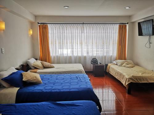 a hotel room with two beds and a window at Hotel Royal Suite in Manizales