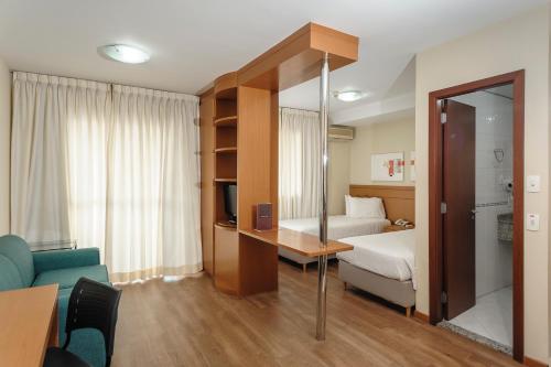 Hotel The Premium في أوساسكو: غرفة في الفندق مع غرفة نوم مع سرير وأريكة