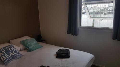 a bedroom with a bed with two pillows and a window at BestMarine Waterchalets Flevo Marina in Lelystad