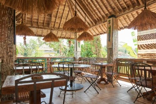 a restaurant with tables and chairs in a building at Royal JJ Ubud Resort & Spa in Ubud