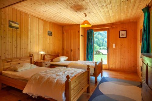 twee bedden in een houten kamer met een raam bij Chalet Clairvaux in Montriond