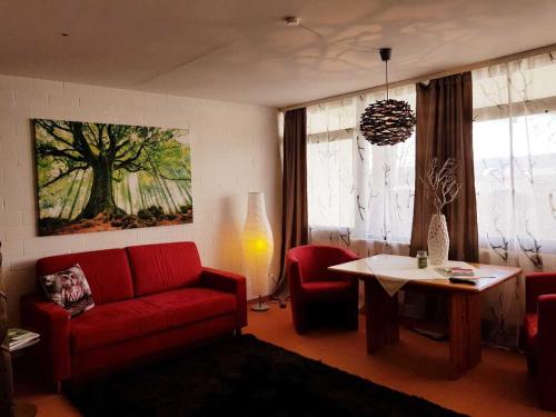 a living room with a red couch and a table at Berg-Bungalows Leinleitertal in Heiligenstadt