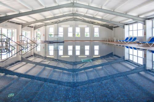 an empty swimming pool with blue chairs in it at Newperran Holiday Park in Newquay