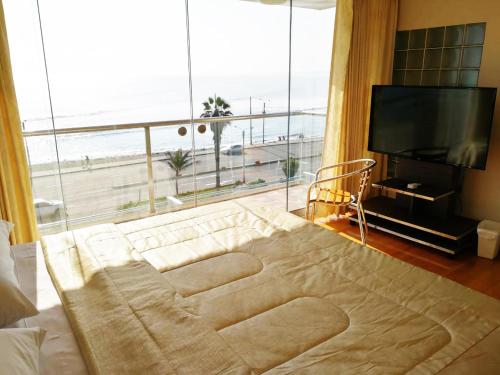 Schlafzimmer mit einem großen Fenster mit Blick auf den Strand in der Unterkunft Caballito de Totora in Huanchaco