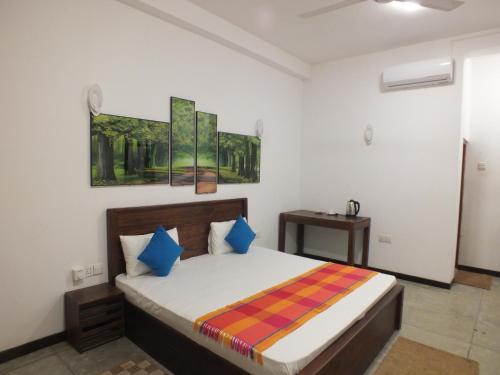 a bedroom with a bed and a painting on the wall at Buddika Safari & Resort in Udawalawe