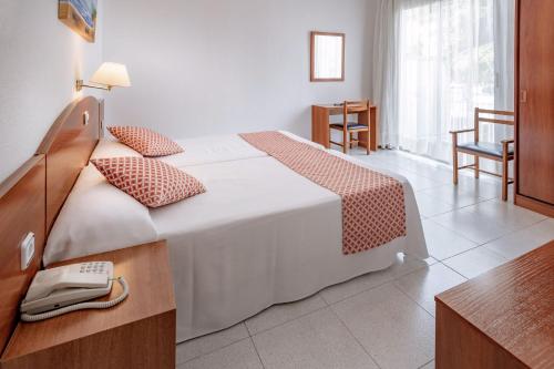 a hotel room with a bed with a phone on it at GHT Balmes, Hotel-Aparthotel&SPLASH in Calella