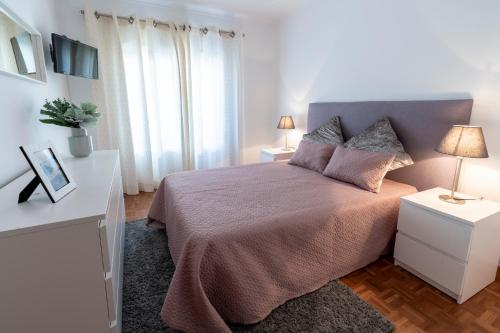 een slaapkamer met een bed en 2 tafels met lampen bij O Veleiro Apartment in Nazaré