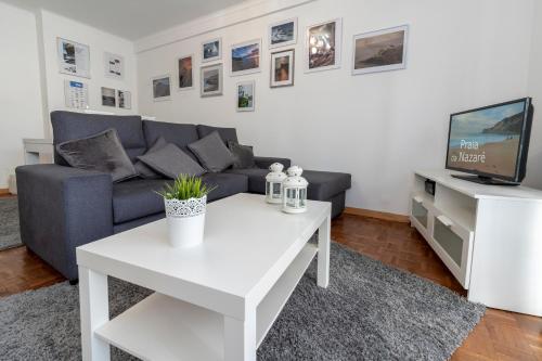 een woonkamer met een bank en een witte salontafel bij O Veleiro Apartment in Nazaré