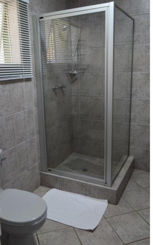 a bathroom with a shower with a toilet at Rabbit Hole Hotel in Krugersdorp