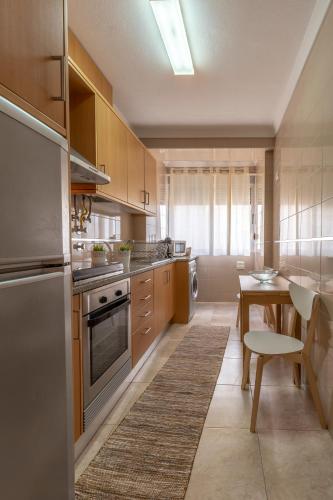 a kitchen with wooden cabinets and a table and a dining room at O Veleiro Apartment in Nazaré