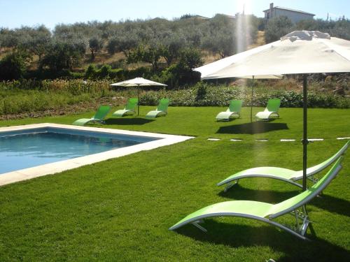 a group of lawn chairs and an umbrella next to a pool at Quinta Rota d' Oliveira in Santa Maria de Émeres