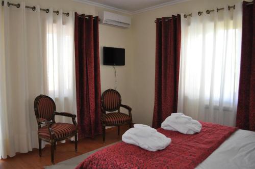 
a hotel room with a bed and a chair at Quinta Rota d' Oliveira in Santa Maria de Émeres
