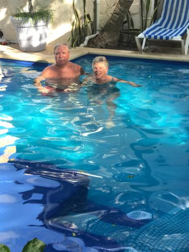 dos hombres están nadando en una piscina en Hotel Amar Inn en Puerto Morelos