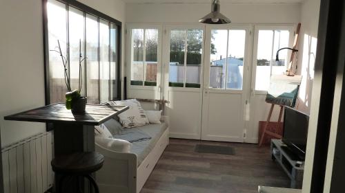 ein Wohnzimmer mit einem Sofa, einem Tisch und Fenstern in der Unterkunft le Paradis in La Noue