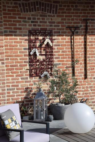 un mur en briques avec une table et une lanterne sur une terrasse dans l'établissement Au cœur de la lys, à Merville