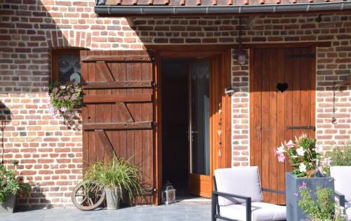 una puerta de madera a un edificio de ladrillo con 2 sillas en Au cœur de la lys, en Merville