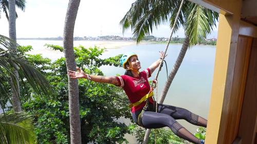 a woman on a zip line between palm trees at Avani Kalutara Resort in Kalutara
